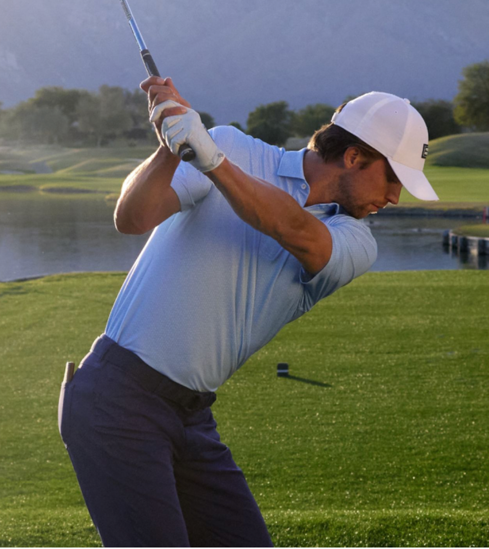Golfer wearing a light blue polo during his backswing
